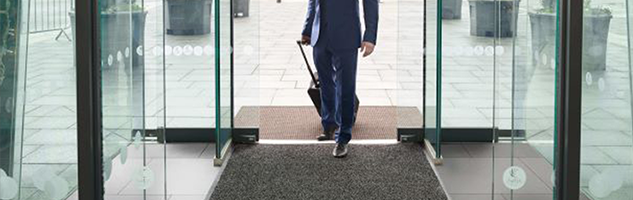 Business man walking over entrance barrier mat