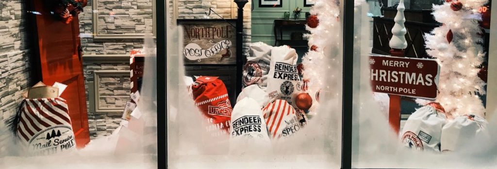 Snowy Festive Christmas window display with Christmas trees and bags of present